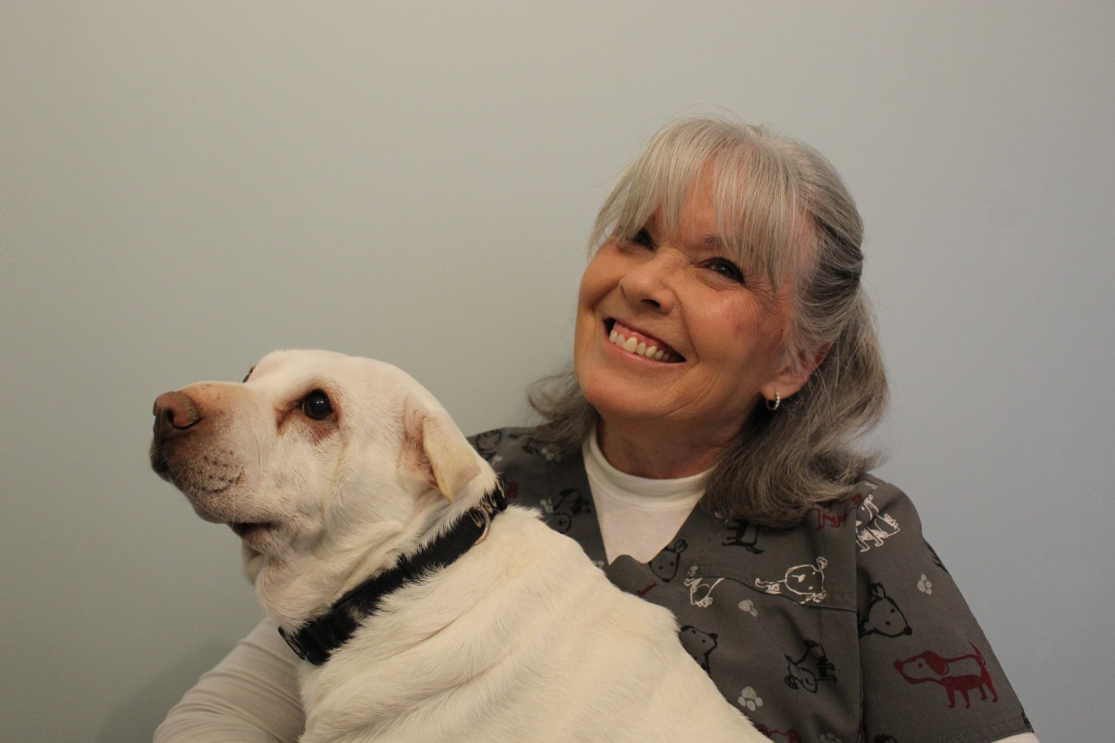 Dr. Donna O'Leary smiling beside a white Labrador